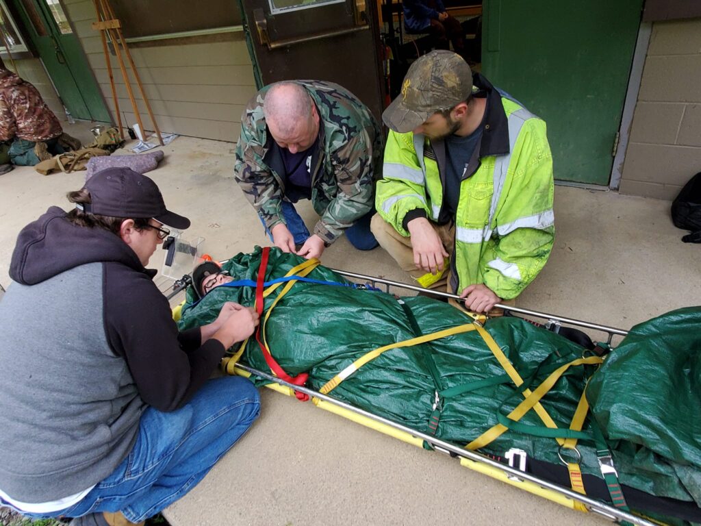 a group of wilderness rescue class attendees tends to a mock patient